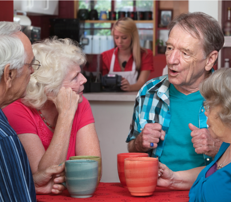 Four senior adults drinking coffee in a cafe