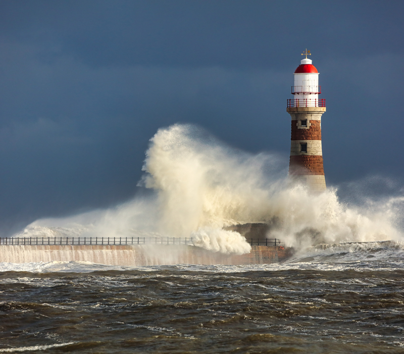 waves crashing against a lighthouse in a storm
