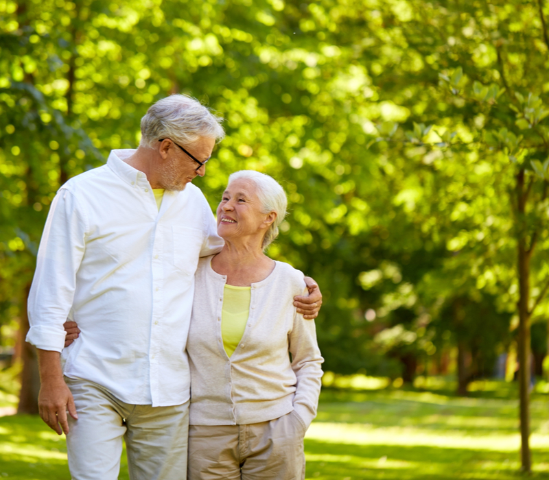 An older couple walking through a park.