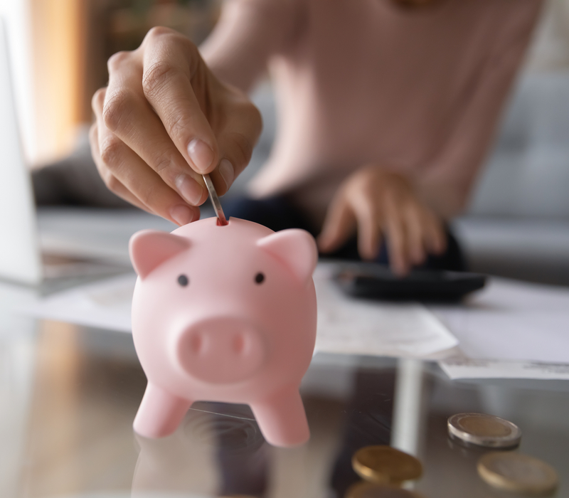 A woman placing money in a piggy bank.