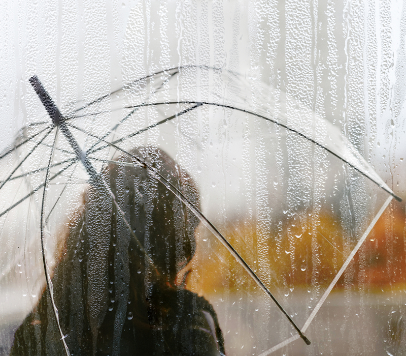 A woman standing under an umbrella.