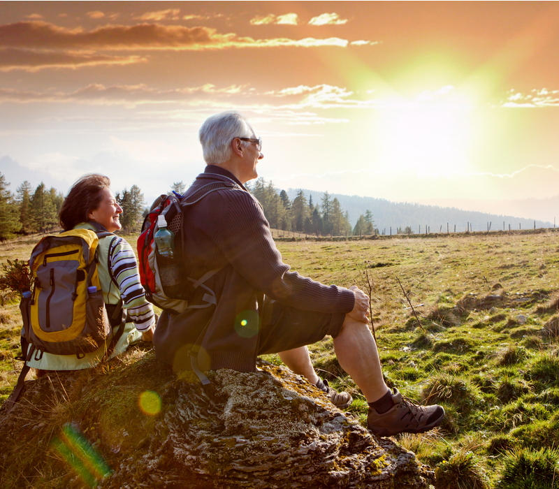 An older couple watching the sunrise on a hike.