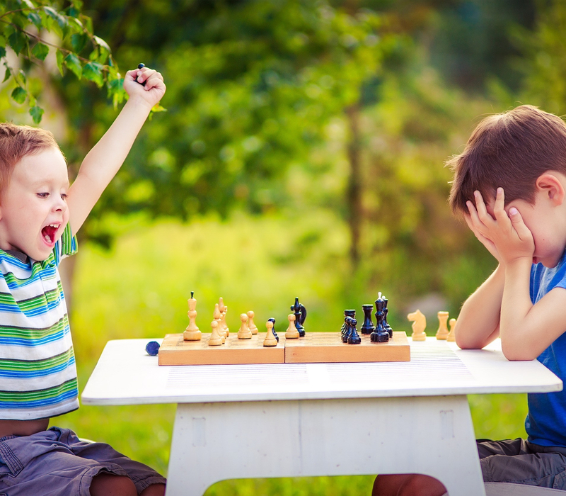 two boys playing chess, one has just won the game and is celebrating