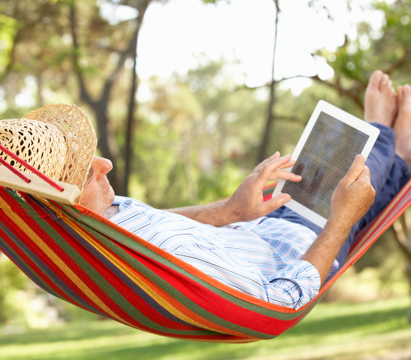 A man in a hammock using a tablet.