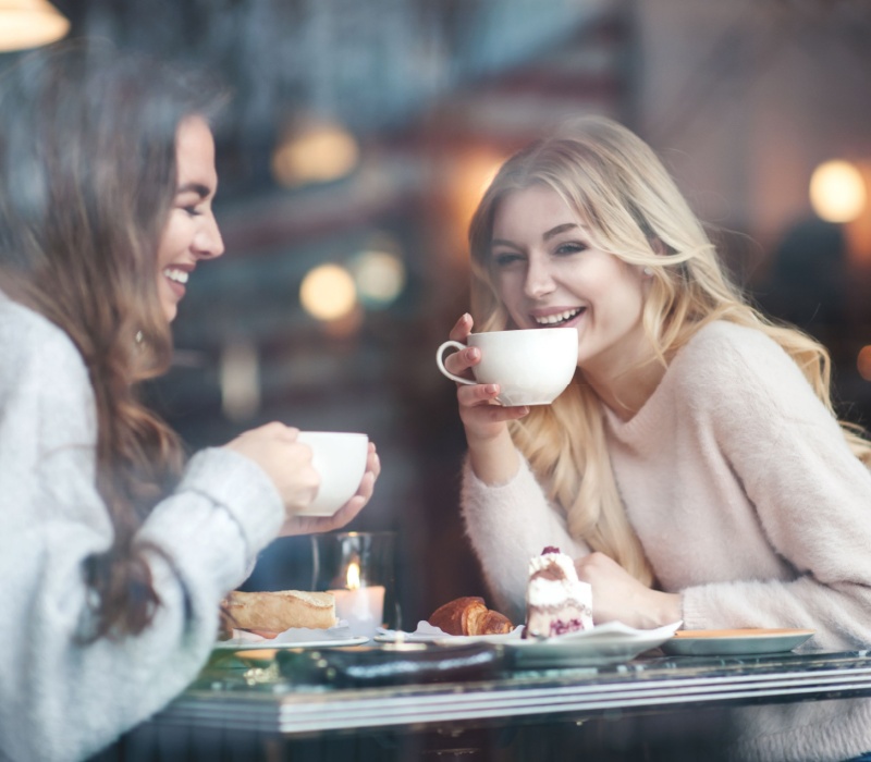 Two women talking and drinking coffee.