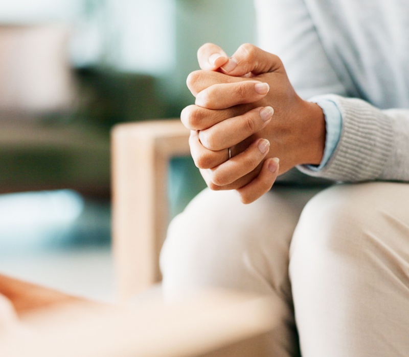 A woman sitting with her hands clasped.