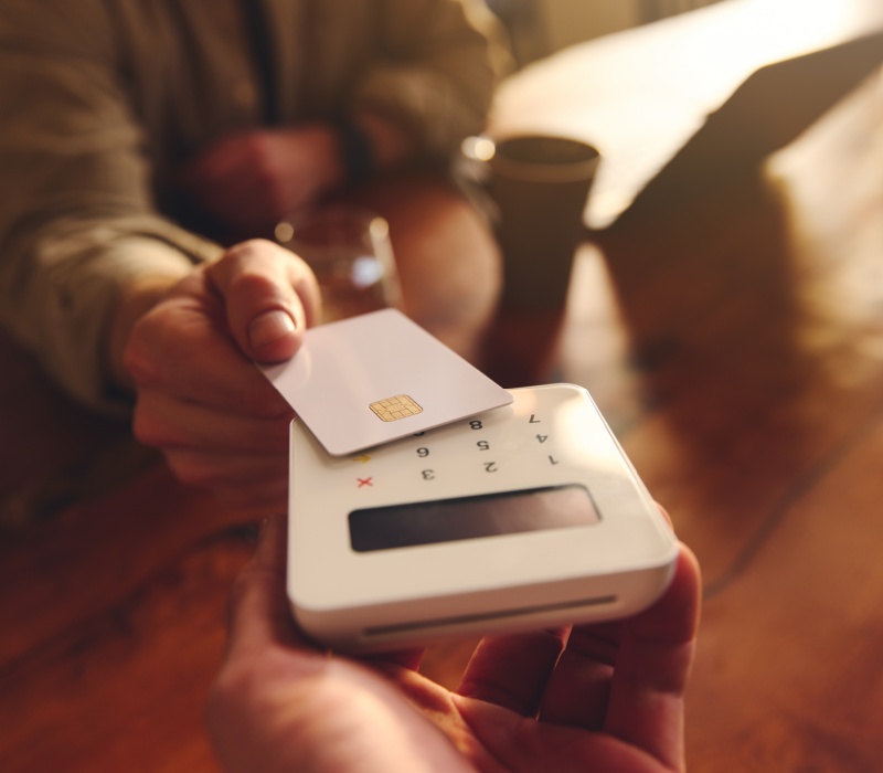 A person using their debit card to pay in a café.